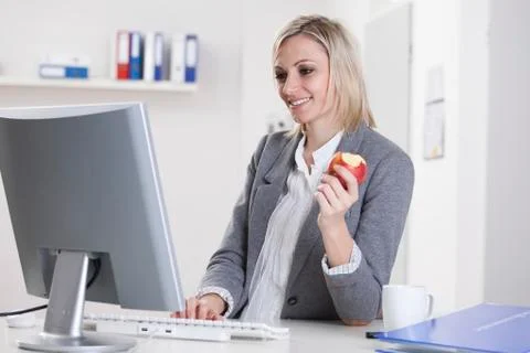 Germany, Bavaria, Munich, Businesswoman using computer and holding apple Stock Photos