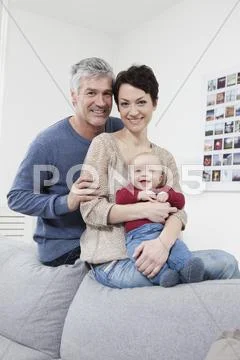 Germany, Bavaria, Munich, Portrait of family sitting on couch, smiling Stock Photos