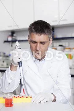 Germany, Bavaria, Munich, Scientist pouring red liquid with pipette in test tube Stock Photos