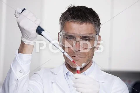Germany, Bavaria, Munich, Scientist pouring red liquid with pipette in test tube Stock Photos