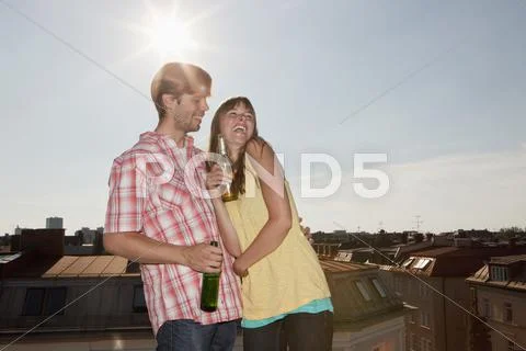 Germany, Bavaria, Munich, Young couple enjoying beer on rooftop Stock Photos
