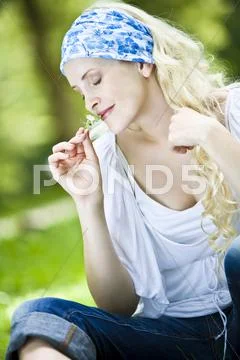 Germany, Bavaria, Munich, Young woman holding blossom, eyes closed Stock Photos