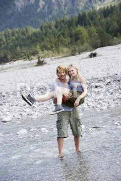 Germany, Bavaria, Tolzer Land, Young man carrying woman in his arms by River Stock Photos