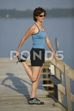 Germany Bavaria, Tutzung, Woman on landing stage stretching leg Stock Photos
