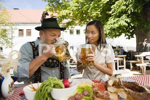 Germany, Bavaria, Upper Bavaria, Bavarian man and Asian woman in beer garden Stock Photos