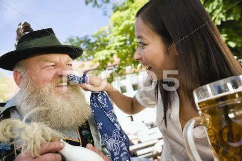 Germany, Bavaria, Upper Bavaria, Bavarian man and Asian woman in beergarden, Stock Photos