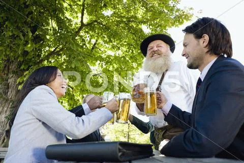 Germany, Bavaria, Upper Bavaria, People in beer garden, clinking glasses Stock Photos