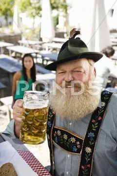 Germany, Bavaria, Upper Bavaria, Senior man in beer garden holding beer stein, Stock Photos