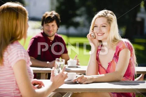 Germany, Bavaria, Upper Bavaria, Young woman in beer garden using phone Stock Photos
