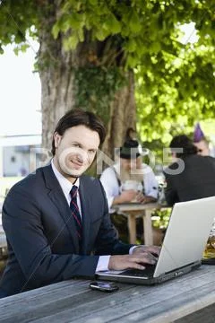 Germany, Bavaria, Upper Bavaria, Young business man in beer garden using laptop, Stock Photos