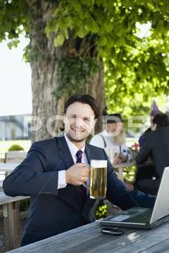 Germany, Bavaria, Upper Bavaria, Young businessman in beergarden holding beer Stock Photos