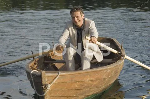 Germany, Bavaria, Wesslinger See, Business man rowing boat in lake after work Stock Photos