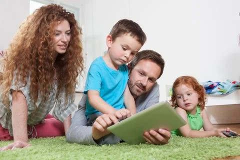 Germany, Berlin, Father using digital tablet with family on floor Stock Photos