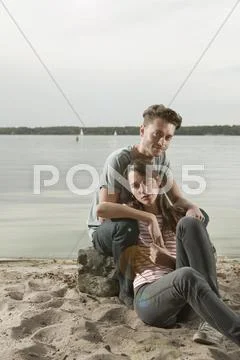Germany, Berlin, Lake Wannsee, Young couple sitting on lakeshore, portrait Stock Photos