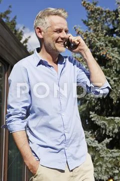 Germany, Berlin, Mature man talking on mobile phone, smiling Stock Photos