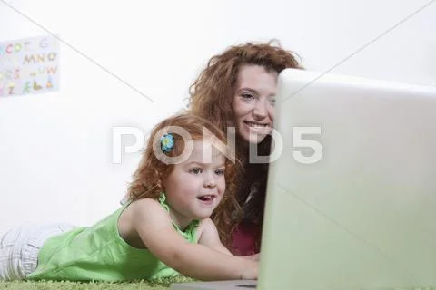 Germany, Berlin, Mother and daughter using laptop on floor Stock Photos
