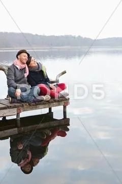 Germany, Berlin, Wandlitz, Couple sitting on pier, smiling Stock Photos