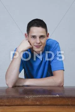 Germany, Berlin, Young man sitting on vaulting horse, smiling, portrait Stock Photos