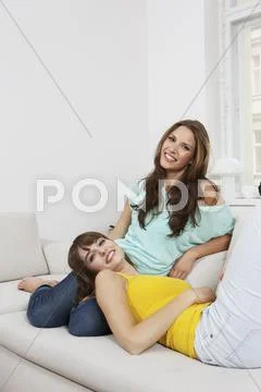 Germany, Berlin, Young women sitting on couch, smiling, portrait Stock Photos