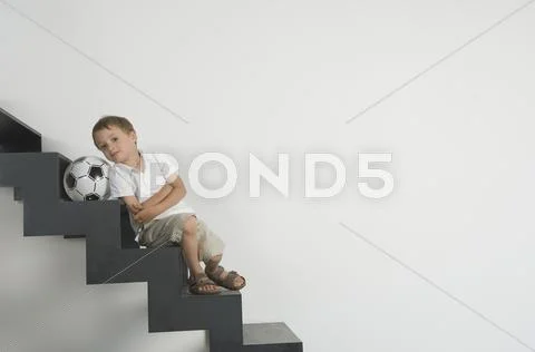 Germany, Boy (4-5 years) sitting on stairs with football, portrait Stock Photos