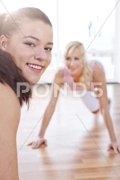 Germany, Brandenburg, Instructor and woman doing exercise in gym, smiling Stock Photos