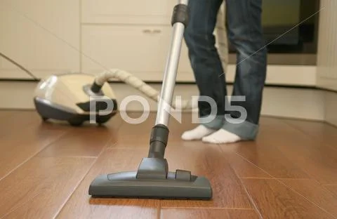 Germany, Brandenburg, Young woman cleaning floor with vacuum cleaner Stock Photos