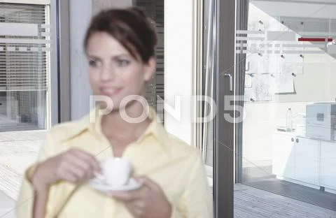 Germany, Cologne, Businesswoman in office taking a break, drinking coffee Stock Photos