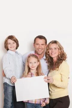Germany, Cologne, Family holding blank carton, smiling, portrait Stock Photos