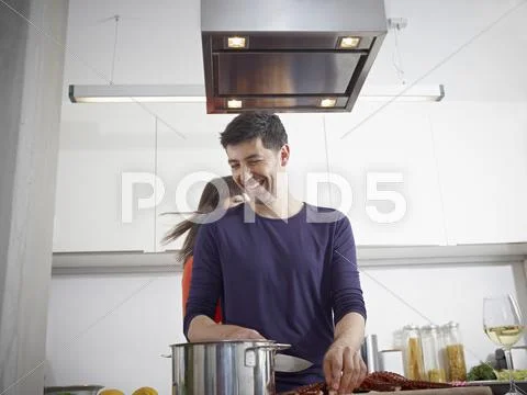 Germany, Cologne, Man and woman cooking together in kitchen Stock Photos