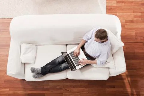 Germany, Cologne, Man on sofa using laptop, elevated view Stock Photos