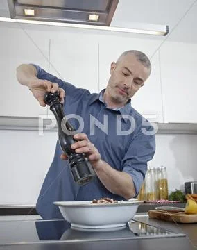 Germany, Cologne, Mature man cooking food in kitchen Stock Photos