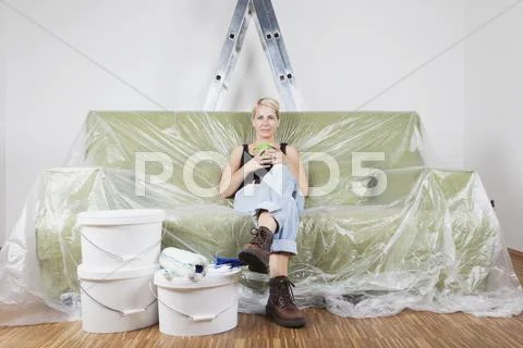 Germany, Cologne, Mature woman enjoying coffee break between wall painting work Stock Photos