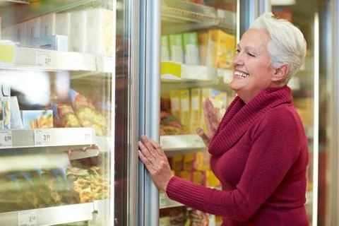 Germany, Cologne, Mature woman standing at freezer in supermarket Stock Photos