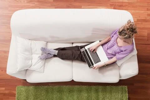 Germany, Cologne, Woman on sofa using laptop, elevated view Stock Photos