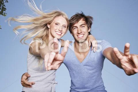 Germany, Cologne, Young couple showing peace sign, smiling, portrait Stock Photos
