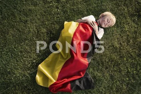 Germany, cologne, young football fan sleeping wrapped in german flag Stock Photos
