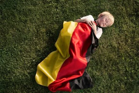 Germany, cologne, young football fan sleeping wrapped in german flag Stock Photos