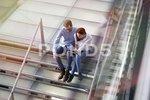 Germany, Cologne, Young woman and mid adult man with tablet at stairs Stock Photos