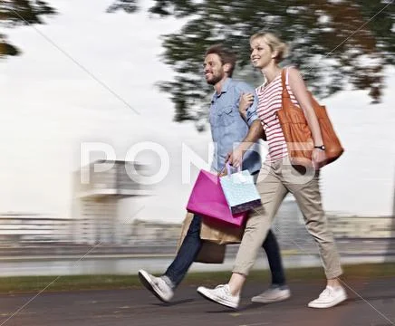 Germany, Cologne, Young woman and mid adult man with shopping bags Stock Photos