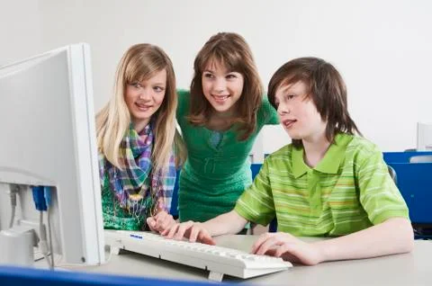 Germany, Emmering, Boy using computer and girls watching, smiling Foto stock