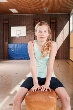 Germany, Emmering, Girl (12-13) sitting on gymnastics vault, portrait Stock Photos