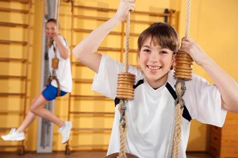 Germany, Emmering, Girls hanging from gymnastic rings, smiling, portrait Stock Photos