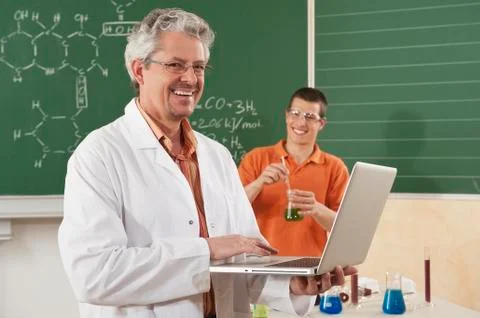 Germany, Emmering, Man using laptop with young man doing experiment in 写真素材