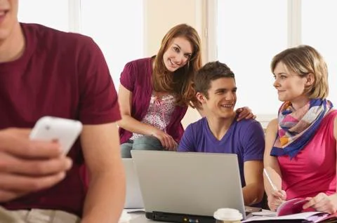 Germany, Emmering, Students using laptop with man holding mobile in foreground Foto stock