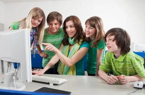 Germany, Emmering, Teacher using computer and explaining students, smiling Foto stock