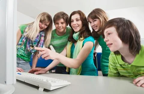 Germany, Emmering, Teacher using computer and explaining students, smiling Stock Photos