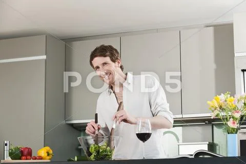 Germany, Hamburg, Man in kitchen preparing salad Stock Photos