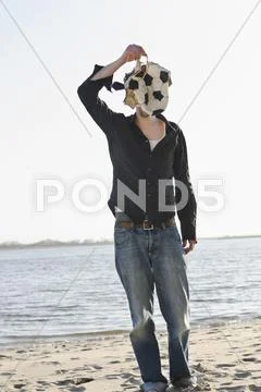 Germany, Hamburg, Mid adult man covering his face with torn football near elbe Stock Photos