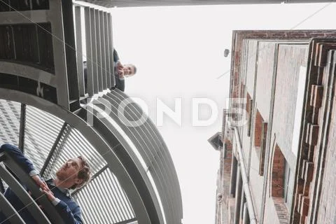 Germany, Hamburg, Two Businessmen on platform of office building looking down, Stock Photos