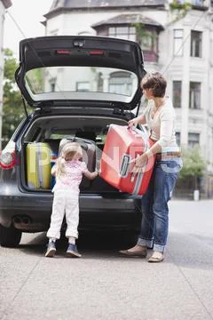 Germany, Leipzig, Mother and daugher (4-5) loading luggage into car Stock Photos